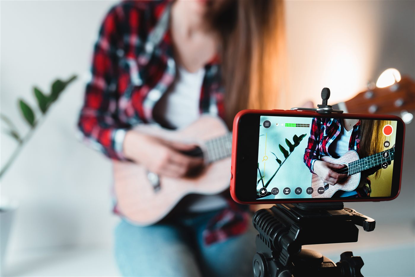 Músico tocando la guitarra siendo grabado con un iPhone en un trípode para transmitir en directo