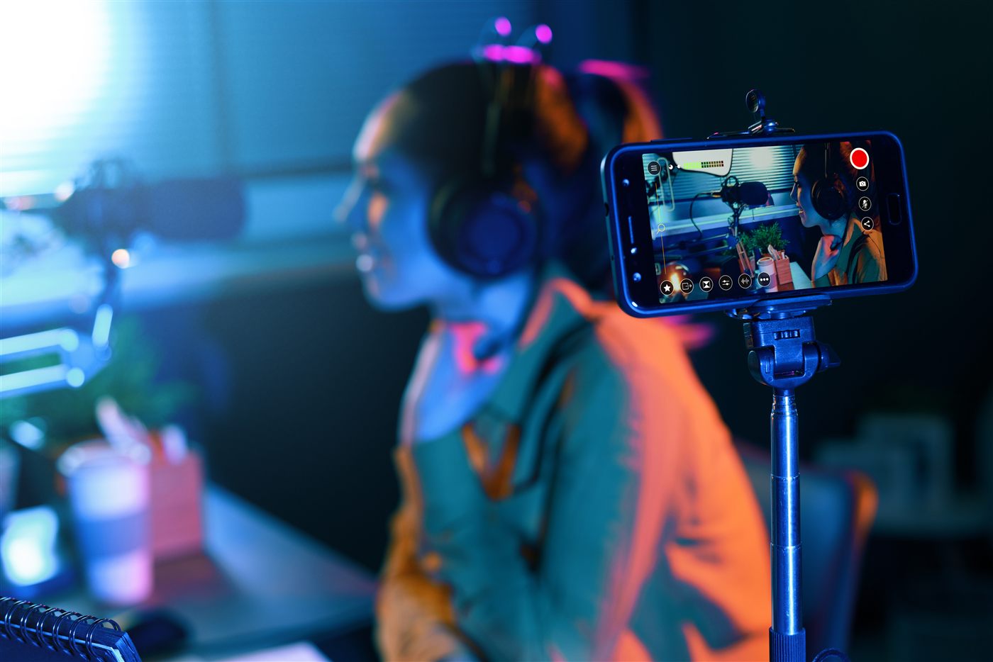 Podcaster grabando con auriculares y micrófono con su iPhone montado en un trípode usando Switcher Studio